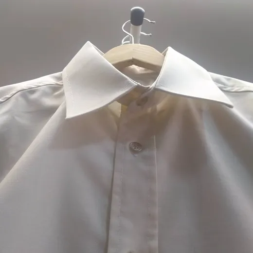 Camisa branca pousada num cabide de madeira