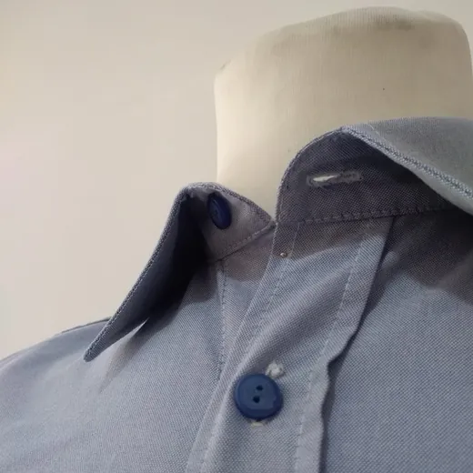 Colarinho de camisa azul-clara com gola interior azul-escura e botão a condizer